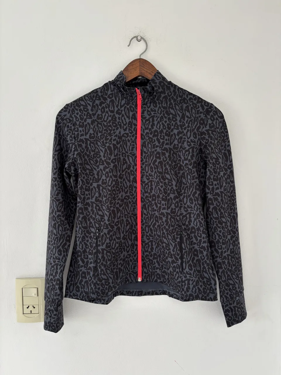 Campera deportiva con estampado animal print en tonos de gris y negro. Cierre frontal rosa