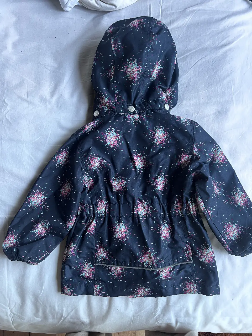Campera impermeable para niña, con capucha y estampado floral. Ideal para días de lluvia.