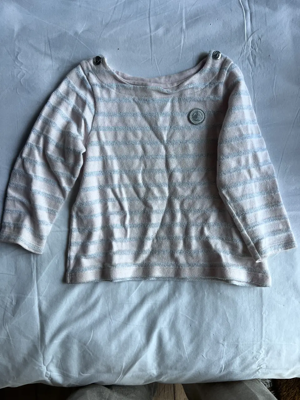 Sweater de niña Petit Bateau a rayas rosas y blancas. Con botones en los hombros y un parche con el logo de la marca. Ideal para un look casual y cómodo.