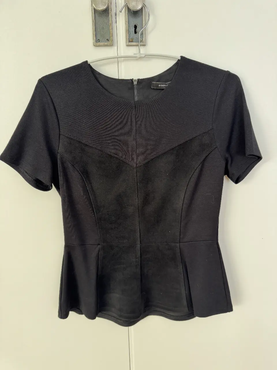 Blusa negra de mujer, con detalle de terciopelo en el frente y corte peplum. Ideal para un look elegante y sofisticado.