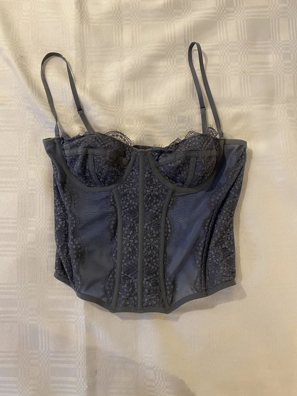 Corpiño estilo corset de encaje y tela gris. Diseño con ballenas y tiras regulables. Ideal para un look sensual y elegante.