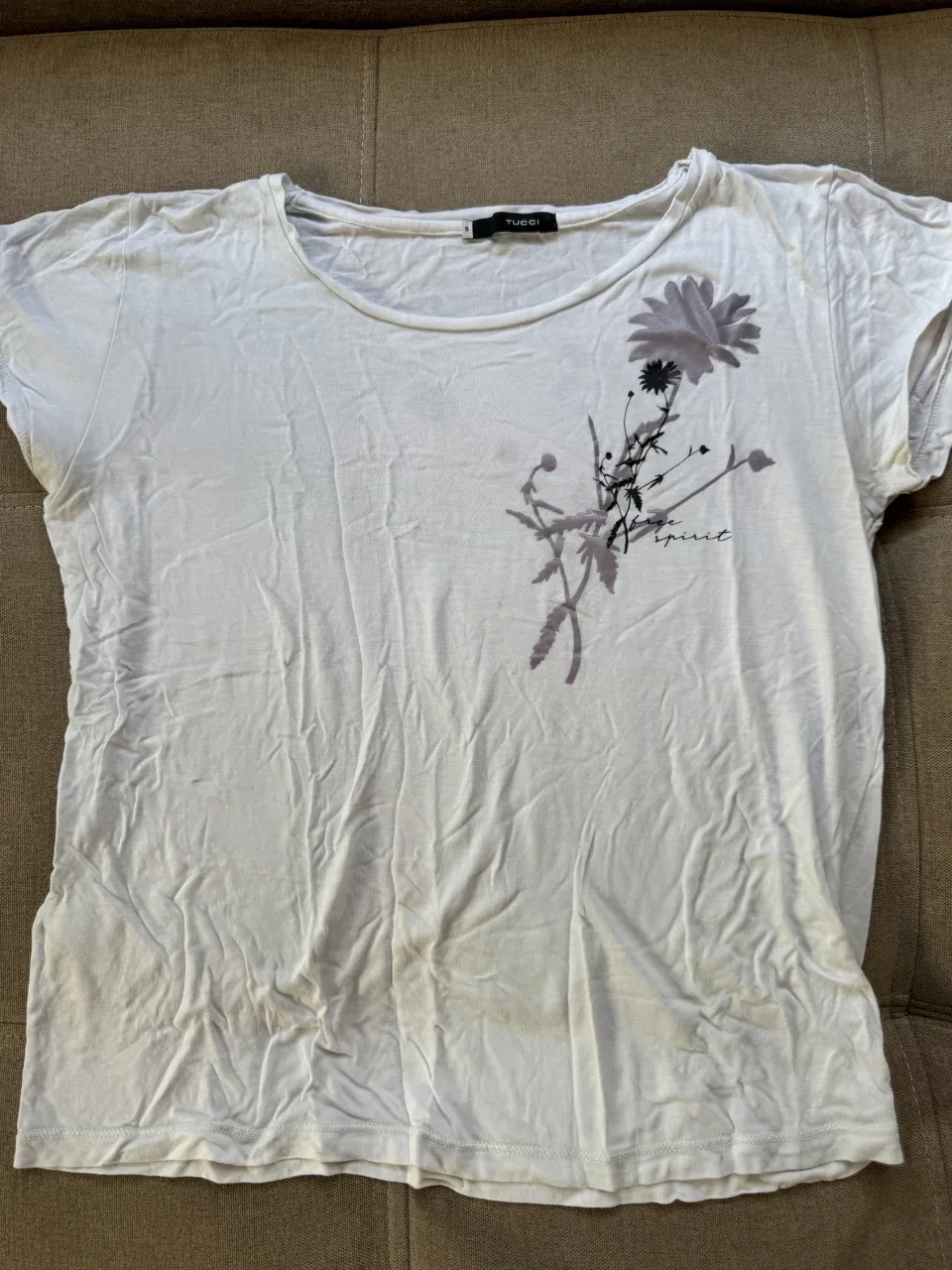 Remera blanca con estampa de flor y ramas en tonos grises y negros. La estampa tiene la palabra "spirit" escrita.
