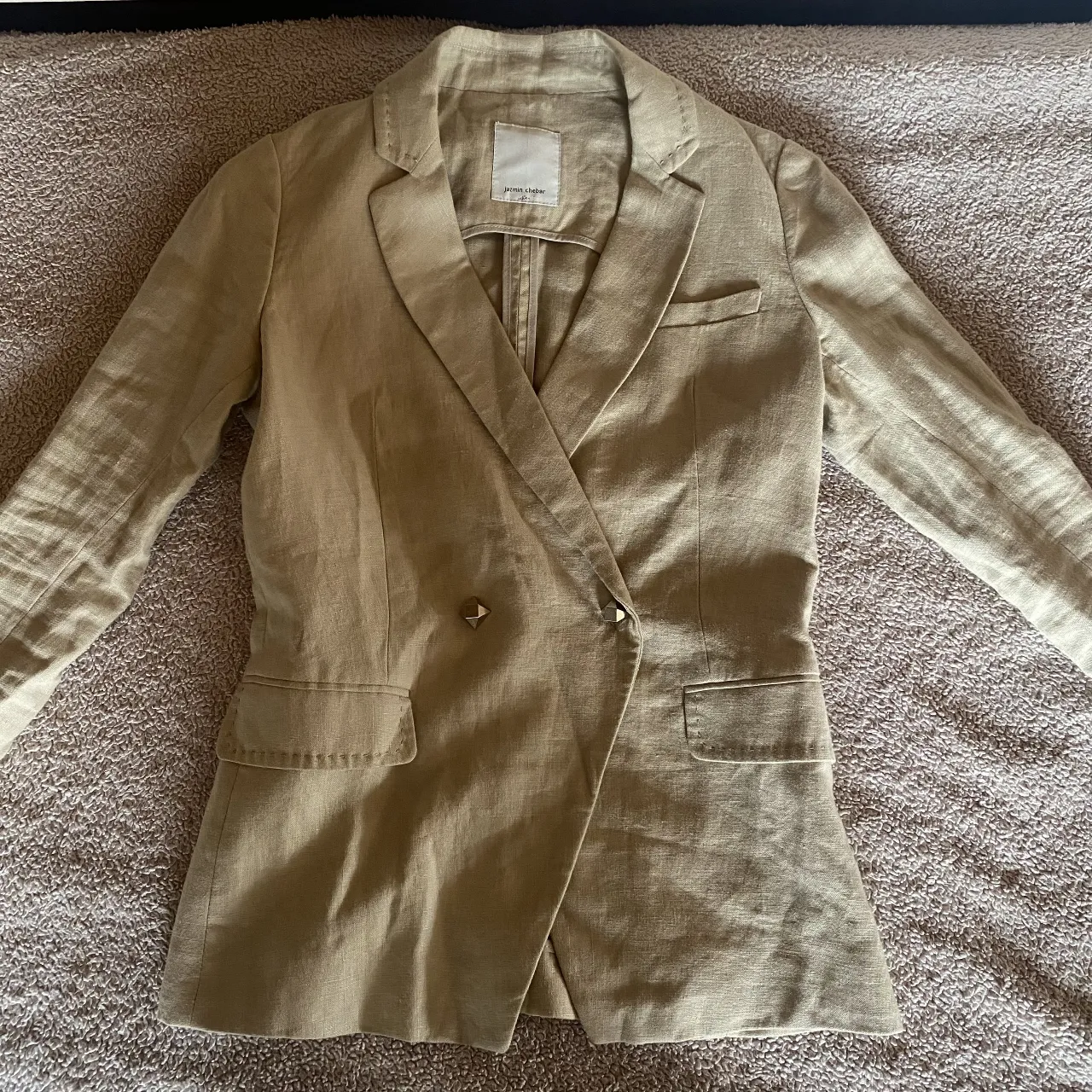 Blazer de lino color tiza, con doble abotonadura y bolsillos frontales. Una prenda súper versátil para elevar cualquier look.