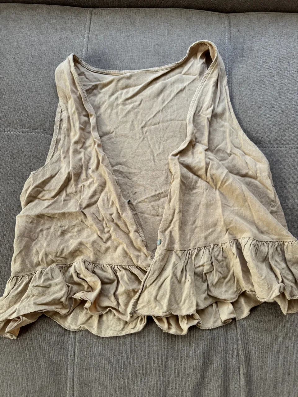 Musculosa color beige con volados en el borde inferior. Posee un solo botón en la parte delantera.