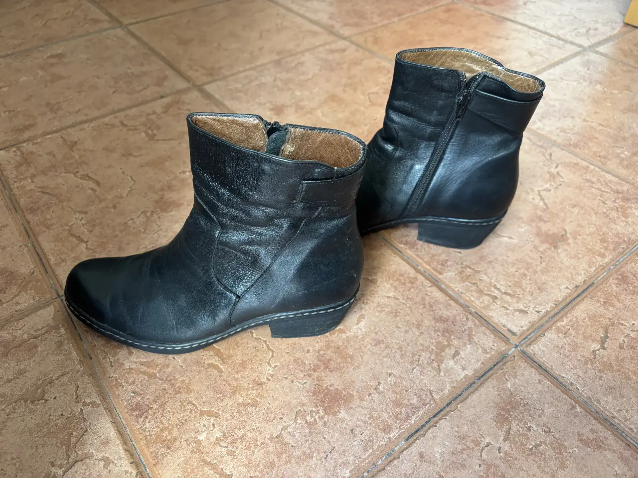 Botines de cuero negro para mujer, con cierre lateral y suela resistente. Ideales para un look casual y moderno.