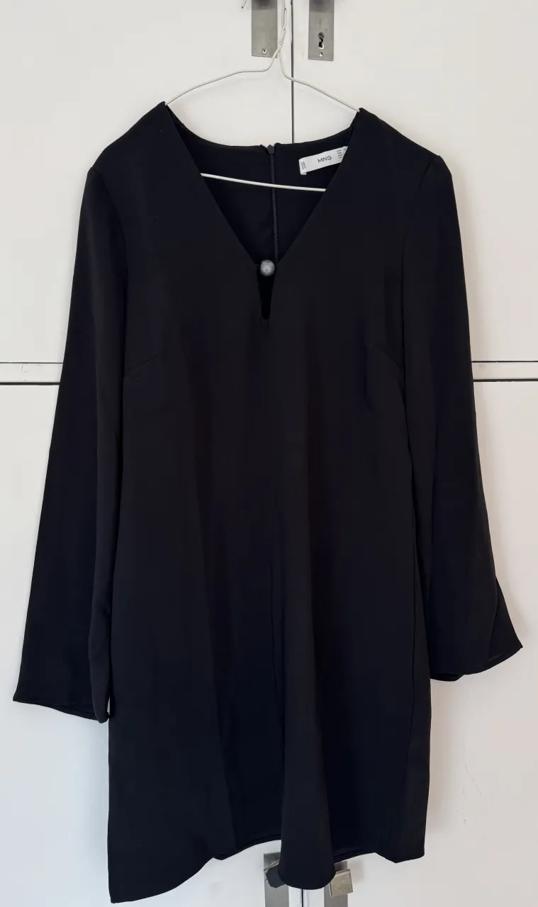 Vestido negro con escote en V y detalle de botón en el escote. Mangas largas.