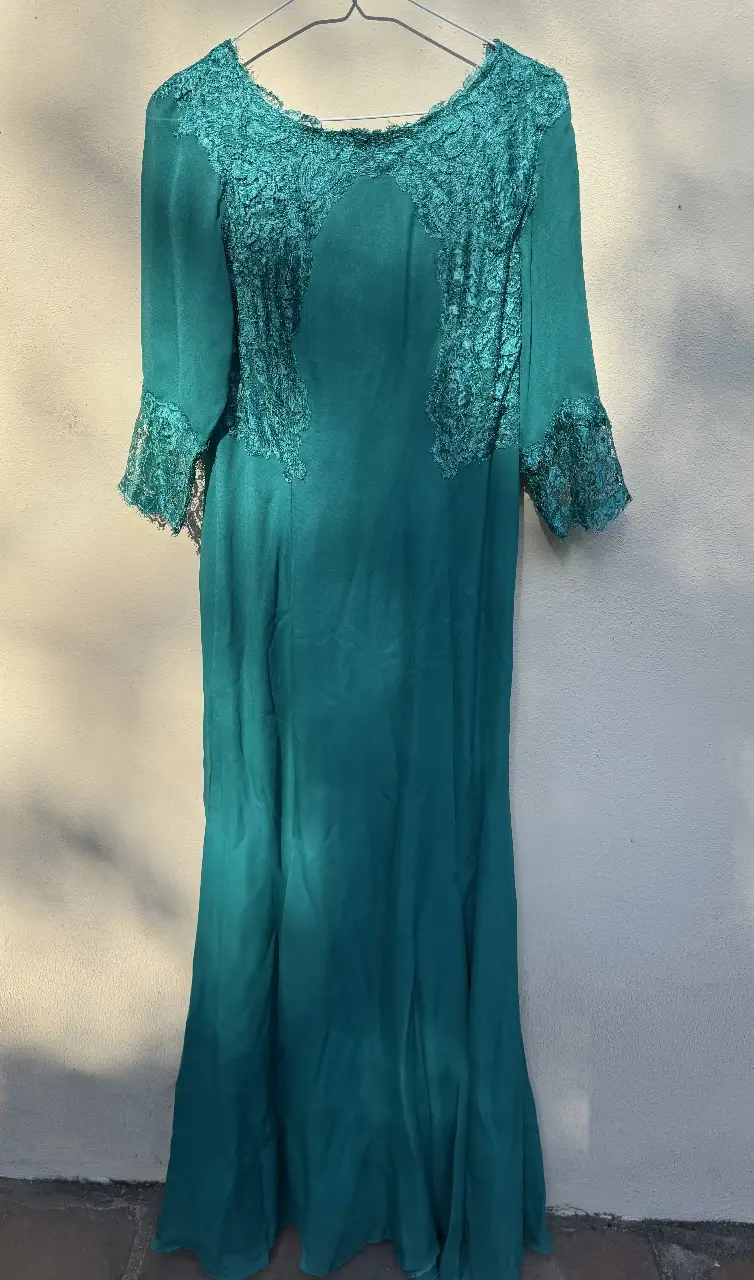 Vestido largo de fiesta en color verde esmeralda, con detalles de encaje en la parte superior y mangas. Ideal para eventos especiales.