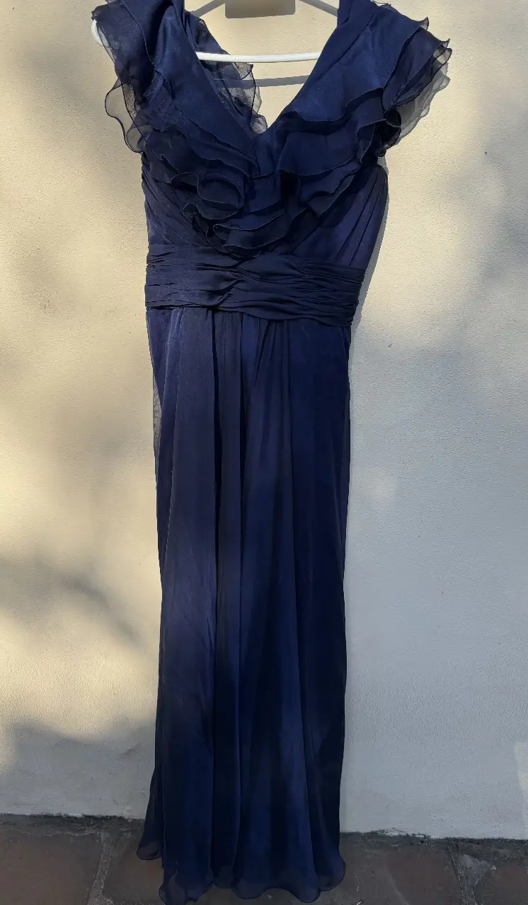 Vestido largo de fiesta en color azul marino, con detalles de volantes en la parte superior y cintura entallada. Ideal para eventos formales y ocasiones especiales.