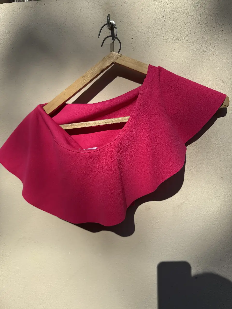 Top fucsia con volados, ideal para un look moderno y femenino. Perfecto para combinar con jeans o faldas.
