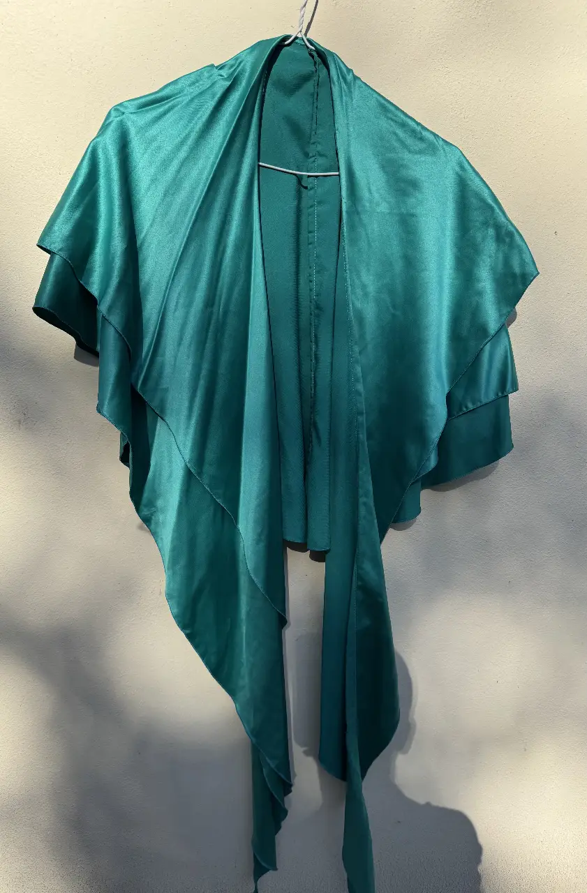 Blusa de satén verde esmeralda con diseño de capa y lazos. Ideal para eventos especiales o para darle un toque elegante a tu look.