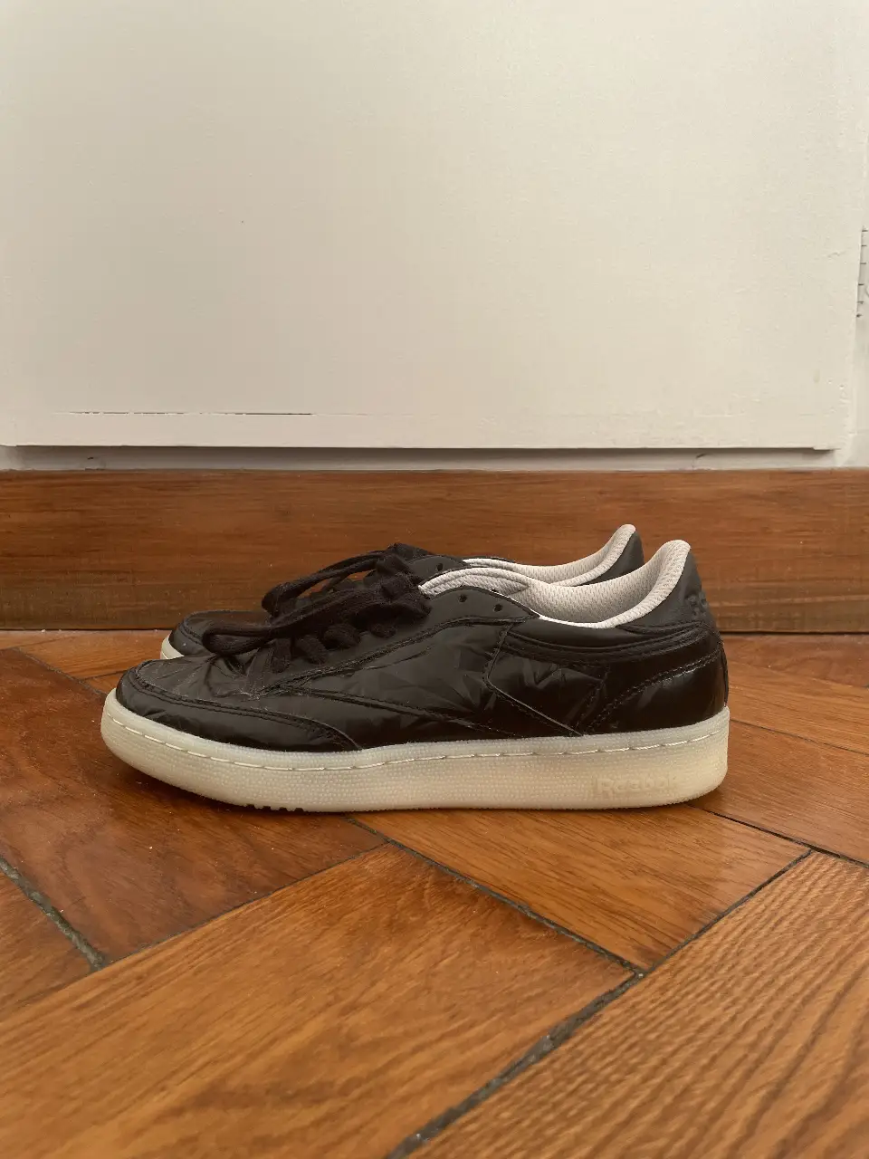 Zapatillas Reebok acharoladas negras con diseño de textura de rombos en la capellada. Suela blanca y detalles en blanco en el interior. Ideales para un look casual y urbano.