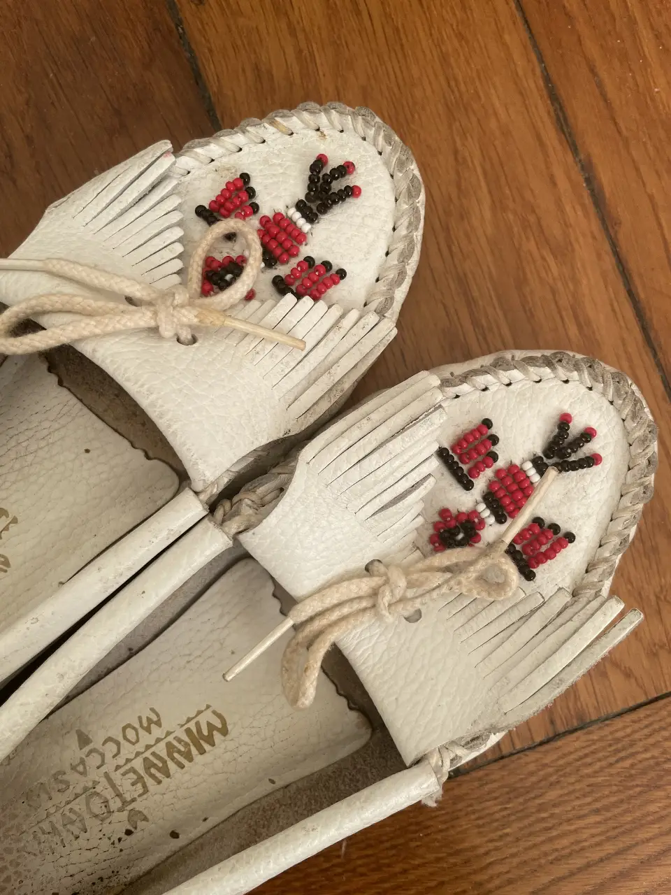 Mocasines vintage blancos de cuero con detalles bordados en mostacilla en rojo y negro. Marca americana Minnetonka Mocassins, modelo clásico Thunderbird. Comprados en Londres. Estilo chic, artesanal y cómodo, ideales para un look casual.