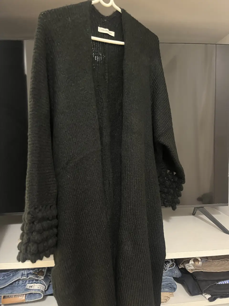 Cardigan largo de tejido grueso en color negro, con mangas con detalle de crochet. Ideal para un look casual y abrigado.