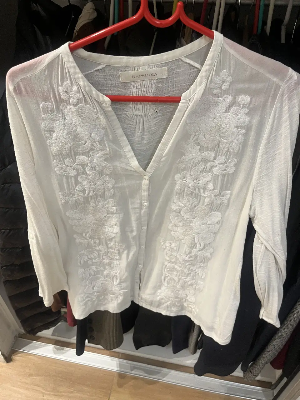Blusa blanca de mujer con bordados florales. Cuello en V y mangas largas. Ideal para un look casual y elegante.