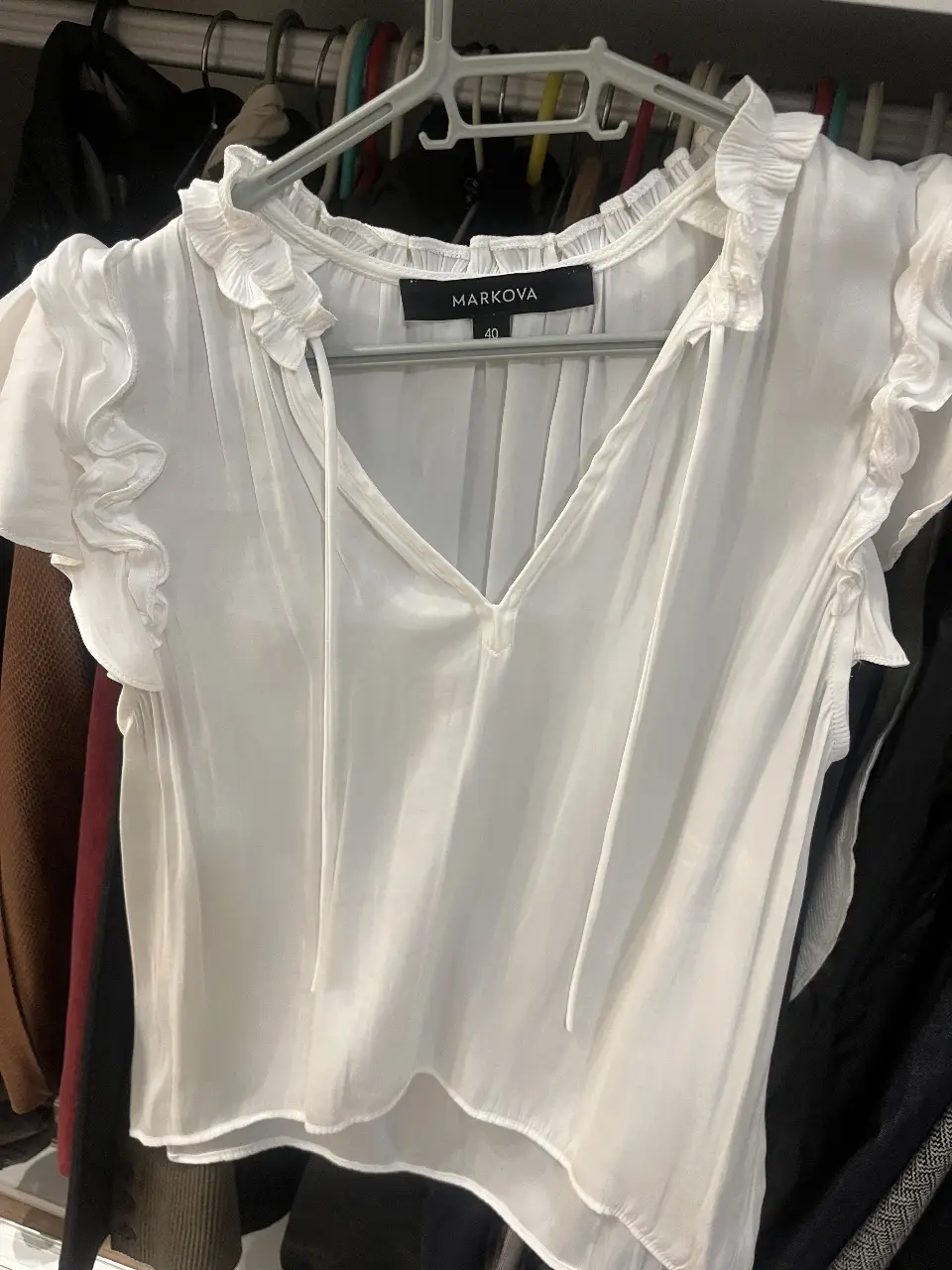Blusa blanca de Markova, con cuello en V y detalles de volados en mangas y cuello. Talle 40.