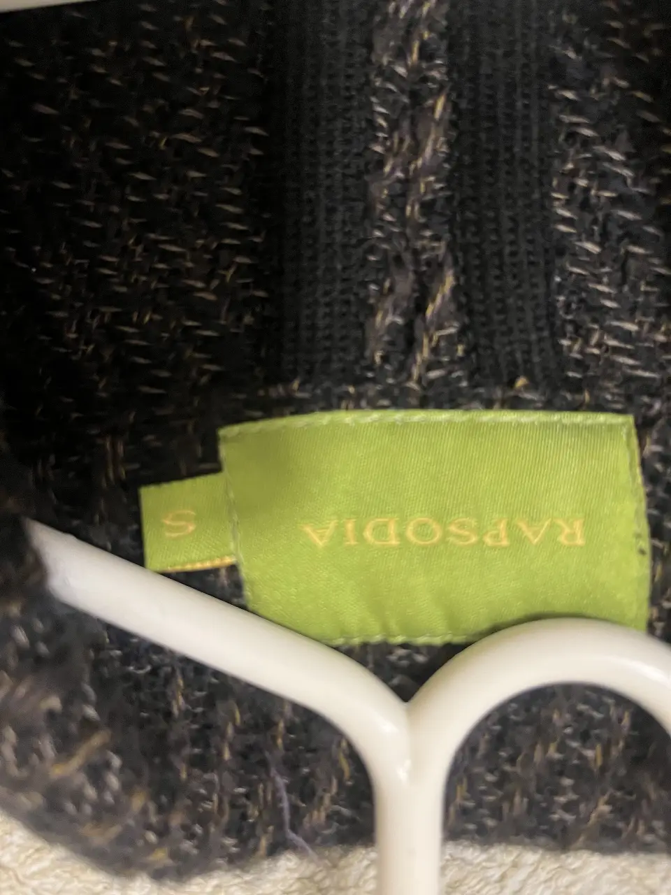 Cardigan de tejido grueso en tonos grises y negro, con botones y detalles en negro. Ideal para un look casual y abrigado.
