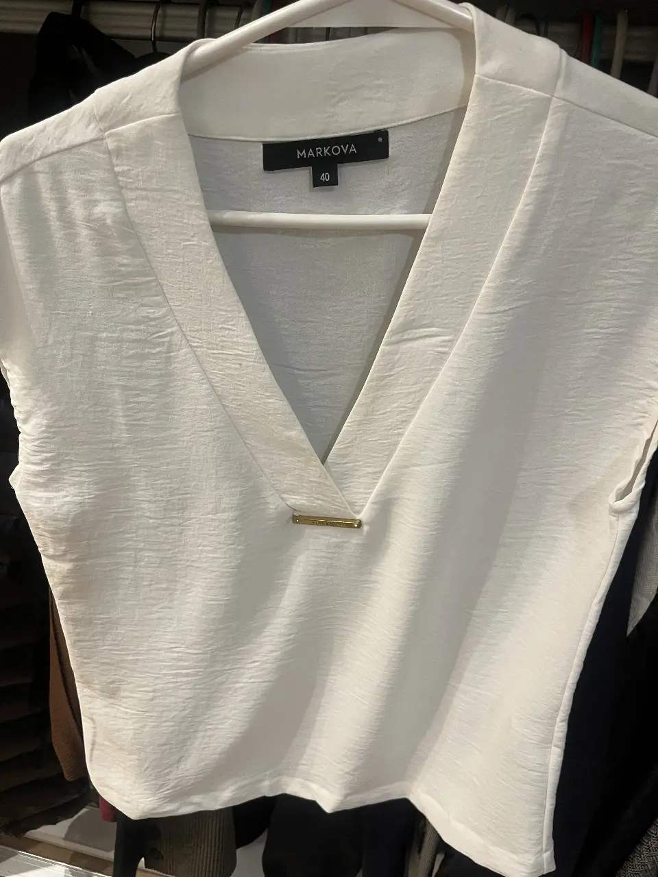 Blusa blanca de la marca Markova, con cuello en V y detalle dorado. Talle 40.