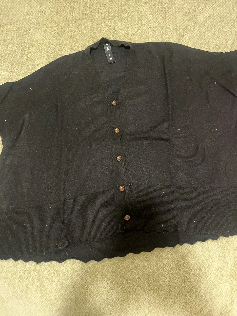 Cardigan negro de tejido suave, con botones y cuello en V. over size.Ideal para un look casual y versátil.