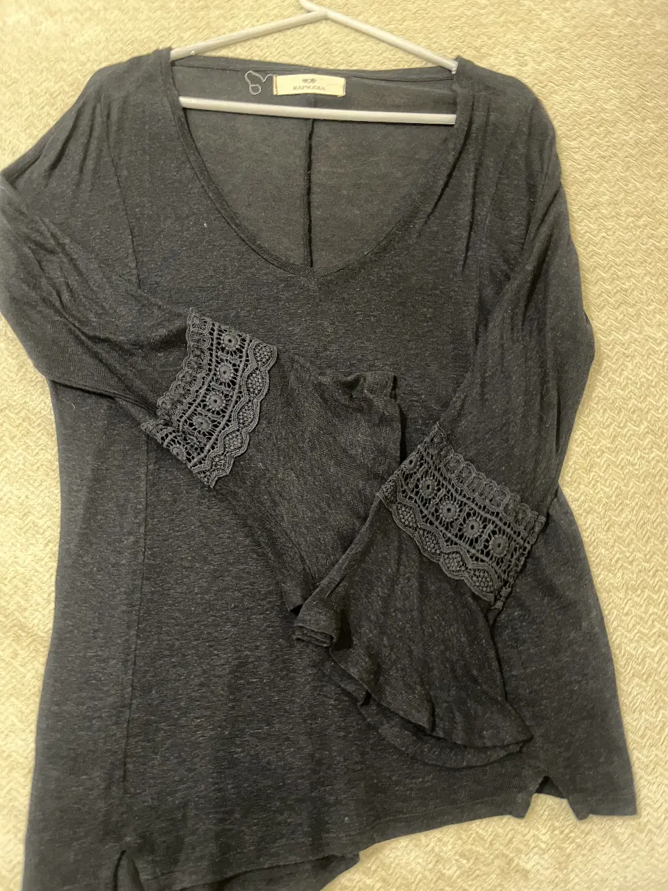 Blusa de manga larga con detalles de encaje en los puños. Cuello en V y corte holgado. gris oscuro. Ideal para un look casual y elegante.