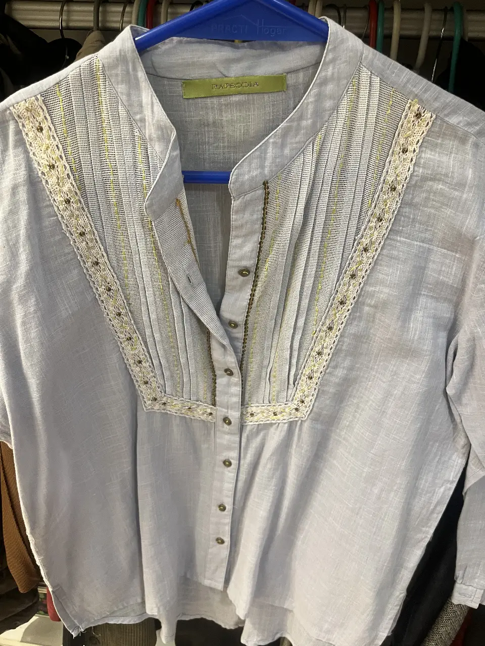 Blusa celeste con detalles bordados en el frente y cuello mao. Ideal para un look casual y elegante.
