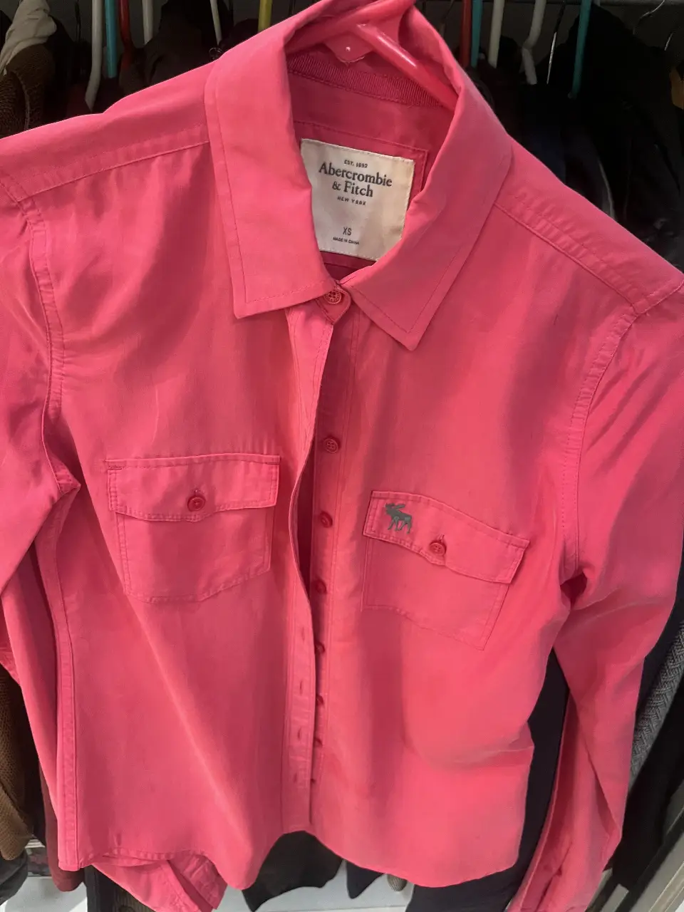 Camisa de mujer Abercrombie & Fitch rosa, talle XS. Confeccionada en tela de algodón. Posee dos bolsillos delanteros y el logo de la marca bordado. Ideal para un look casual y moderno.