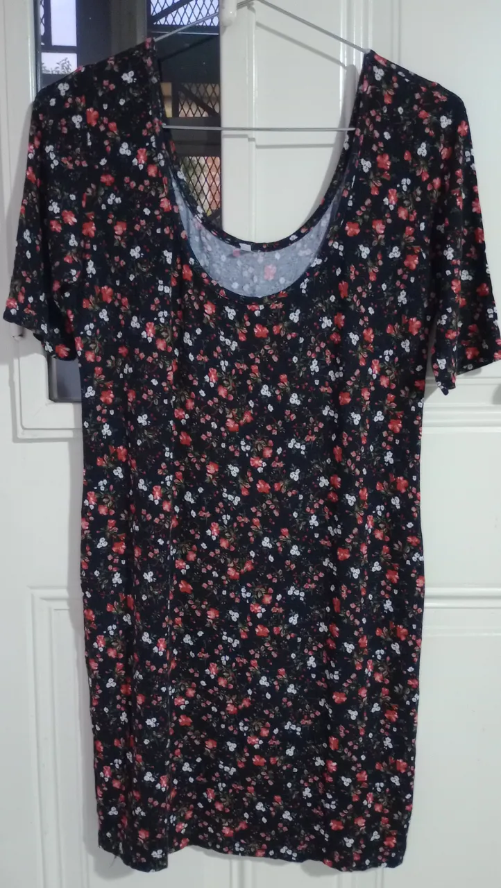 Remera estampada con flores pequeñas en tonos rojos y blancos sobre fondo negro. Posee mangas cortas y escote redondo.