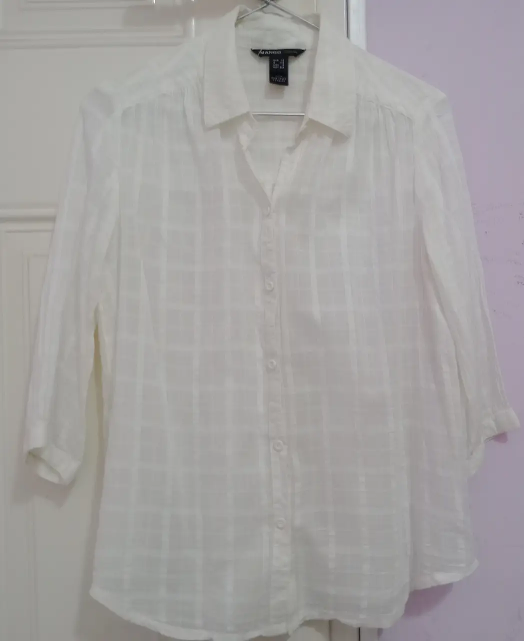 Camisa blanca de manga 3/4 con diseño a cuadros sutiles. Ideal para un look casual y fresco. Marca Mango.