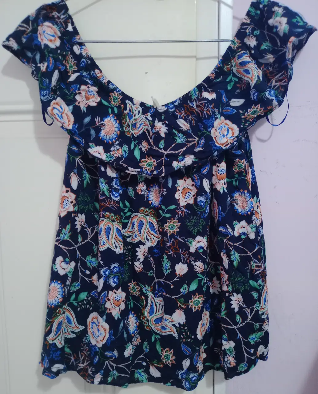 Blusa de mujer con estampado floral en tonos azules y blancos. Diseño off-shoulder con volados en el escote y mangas cortas. Ideal para un look fresco y femenino.
