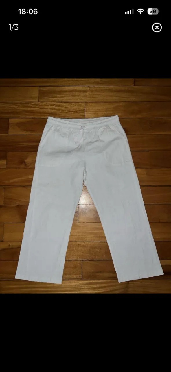 Pantalón blanco de lino tipo capri con cordón ajustable en la cintura y bolsillos delanteros.   