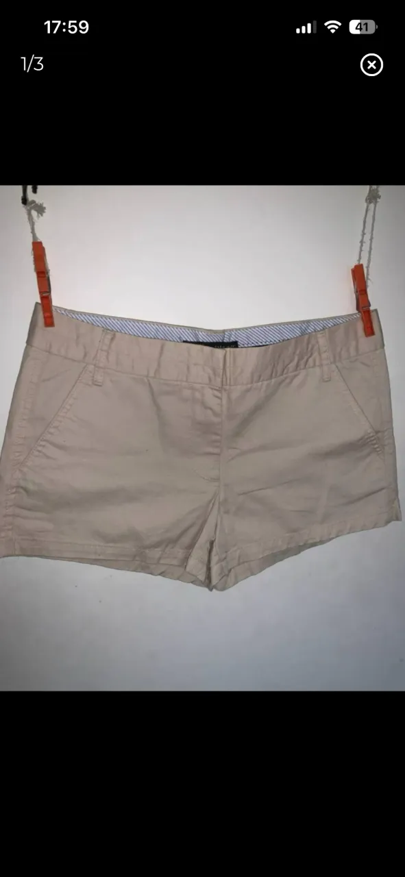 Short de vestir color beige con bolsillos delanteros y traseros. Cintura con presillas y detalles de tela a rayas en el interior. Tiro bajo