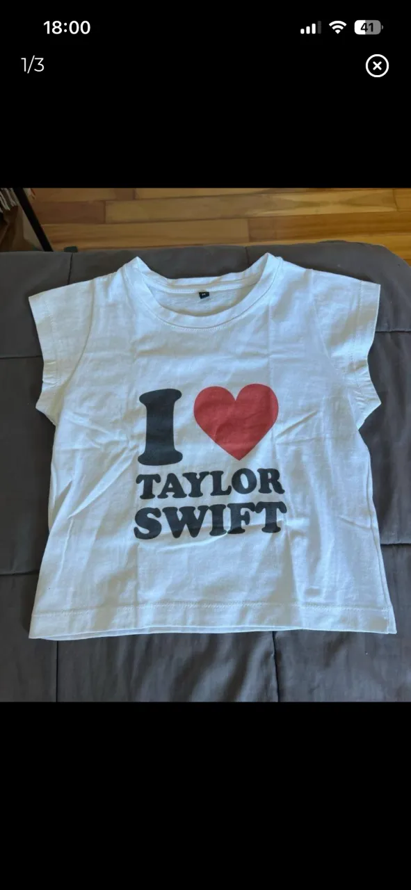 Remera baby tee blanca con estampa "I ❤️ TAYLOR SWIFT" en negro y rojo.