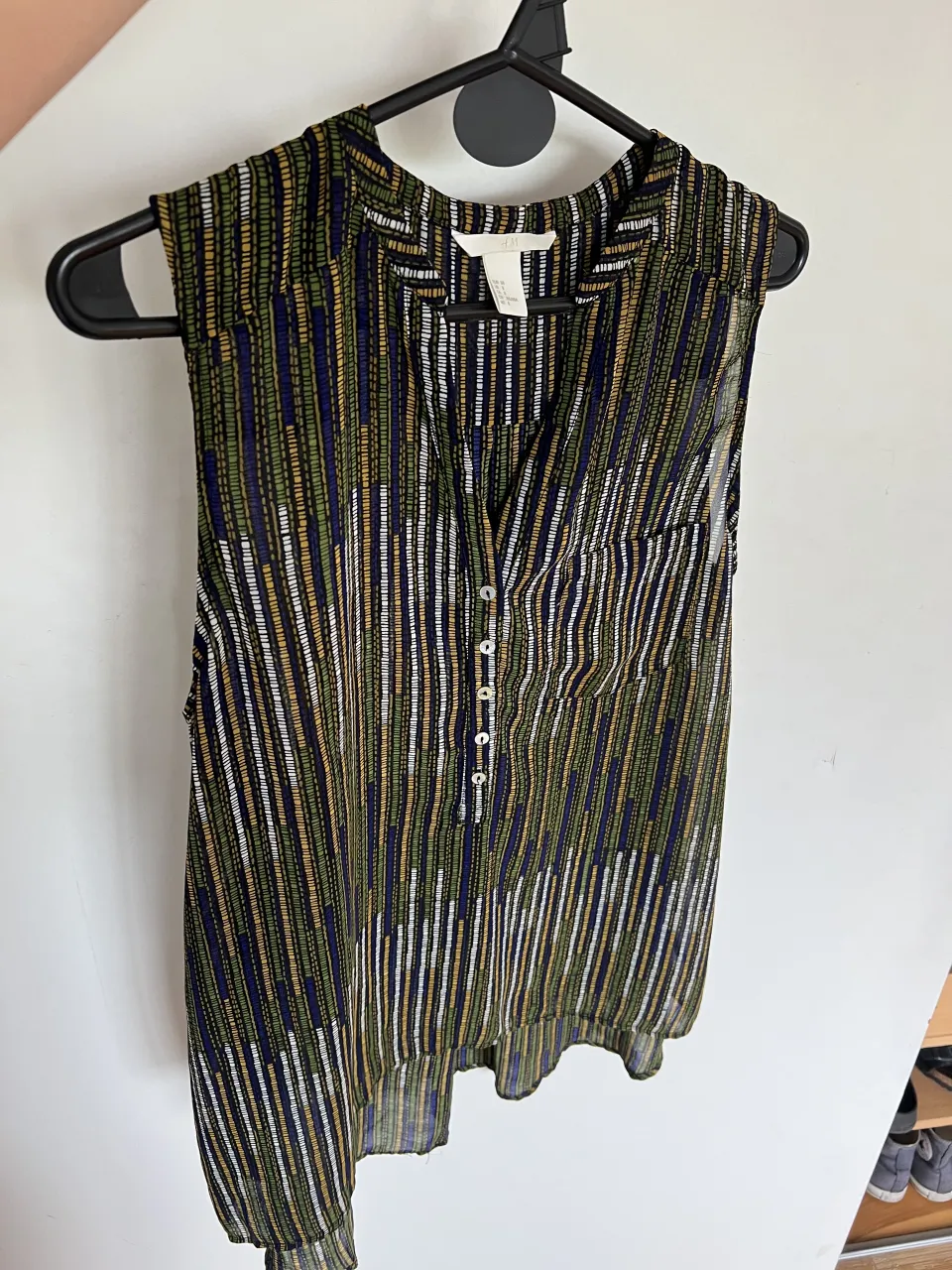 Remera sin mangas con estampado de rayas verticales en varios colores. Posee cuello en V y botones en la parte superior. Tiene un bolsillo en el frente. Marca H&M Talle 38(M)