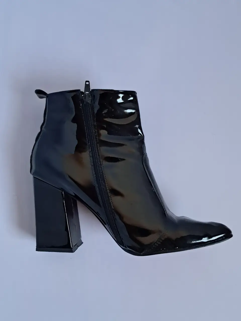 Botines de charol negros con taco ancho y punta fina. Diseño elegante con suela roja. Ideales para darle un toque sofisticado a cualquier look.