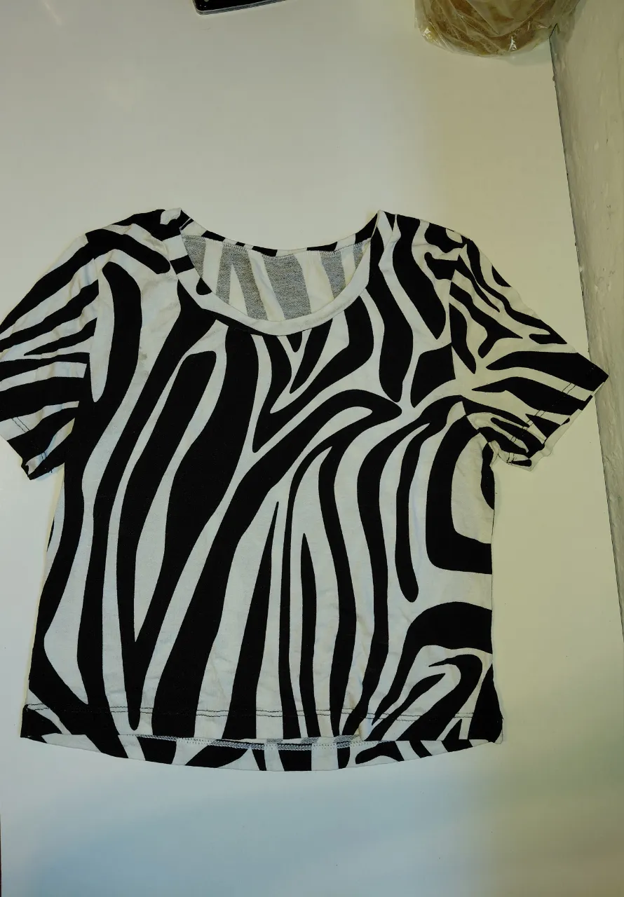 Remera blanca con estampa de cebra en negro. Manga corta y cuello redondo.