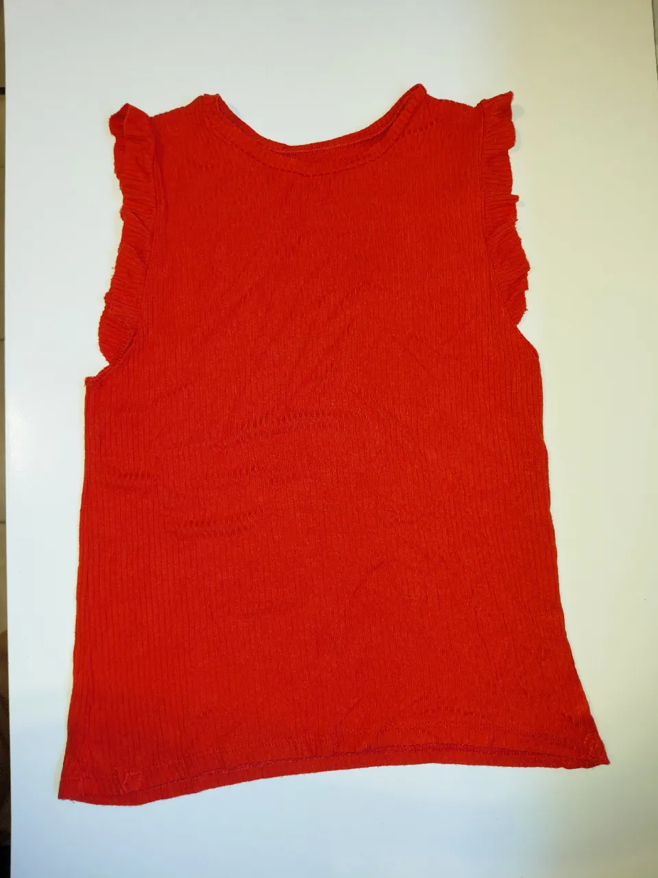 Musculosa roja de tejido acanalado con volados en los hombros.