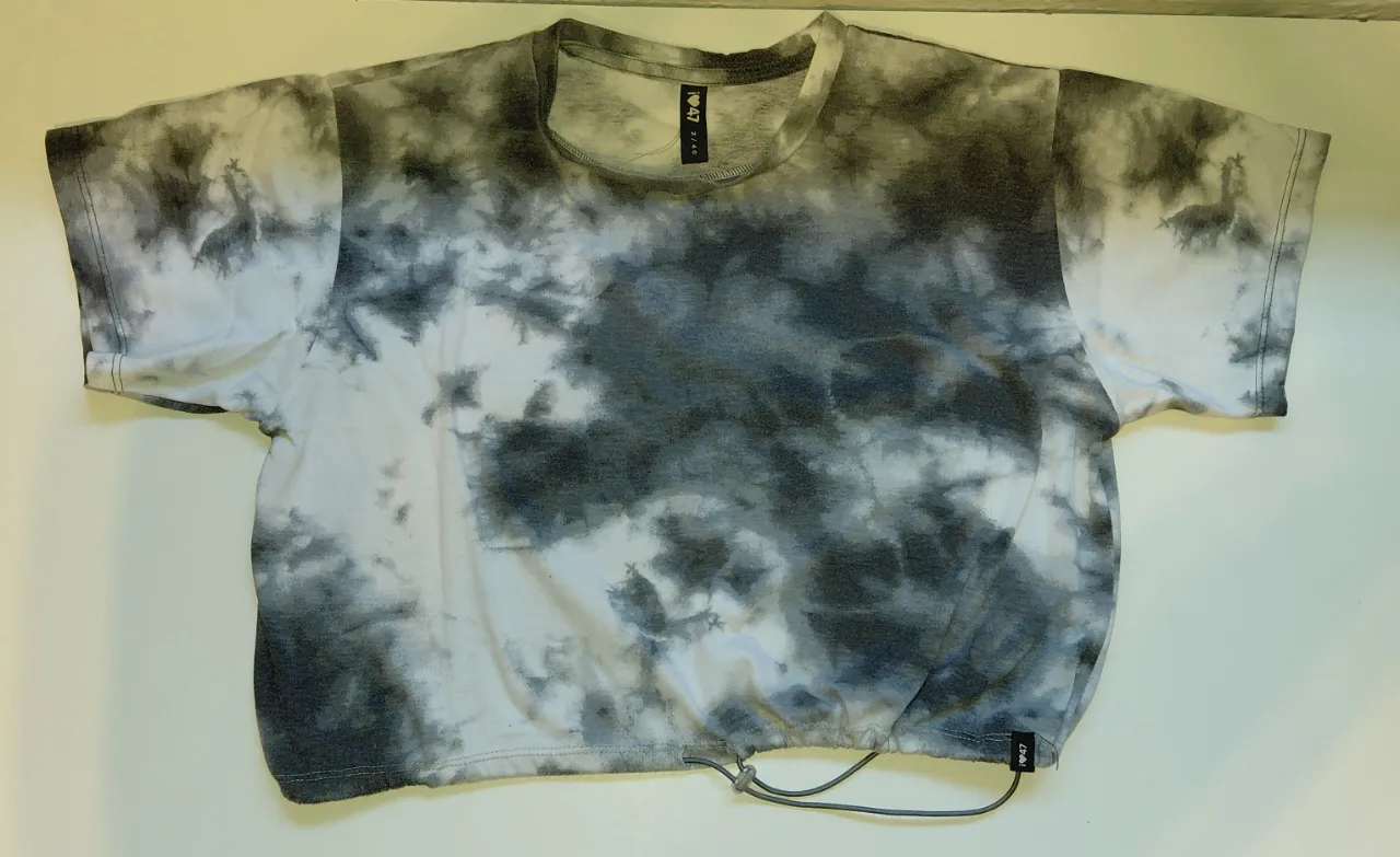Remera crop con estampa tie dye en blanco y gris. Posee cordón ajustable en la cintura.