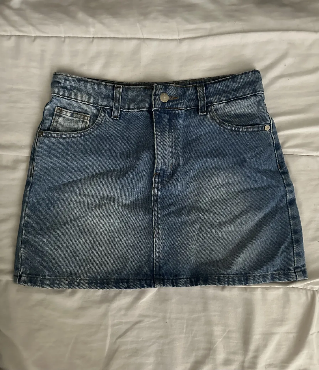 Pollera de jean tiro alto, con bolsillos y detalles desgastados. Un clásico que no puede faltar en tu guardarropa, ideal para combinar con remeras, tops o camisas. ¡Un must-have para cualquier ocasión!