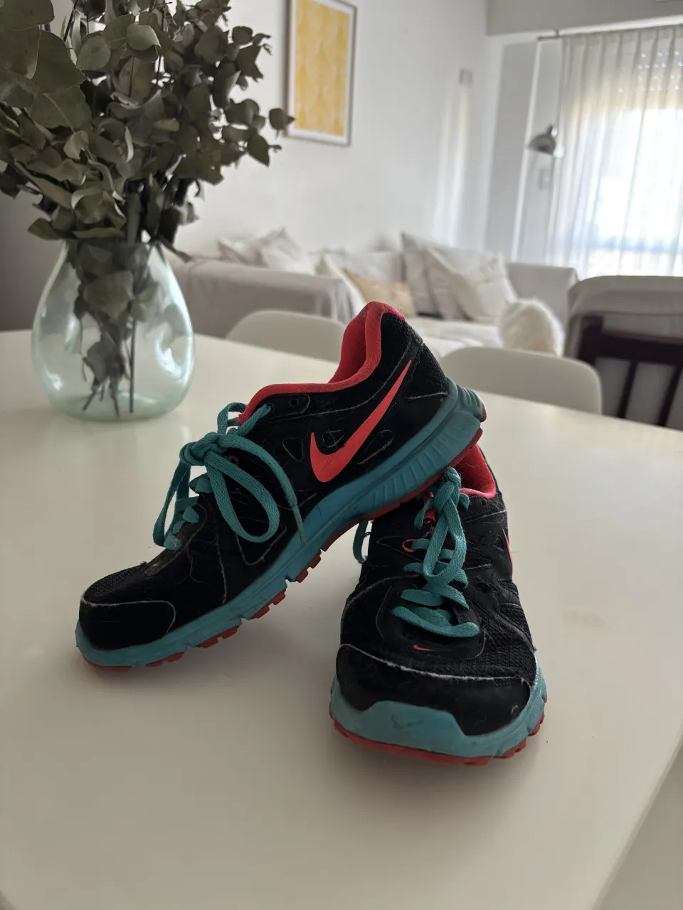 Zapatillas deportivas Nike negras con detalles en color coral y azul. Cordones celestes y suela bicolor.