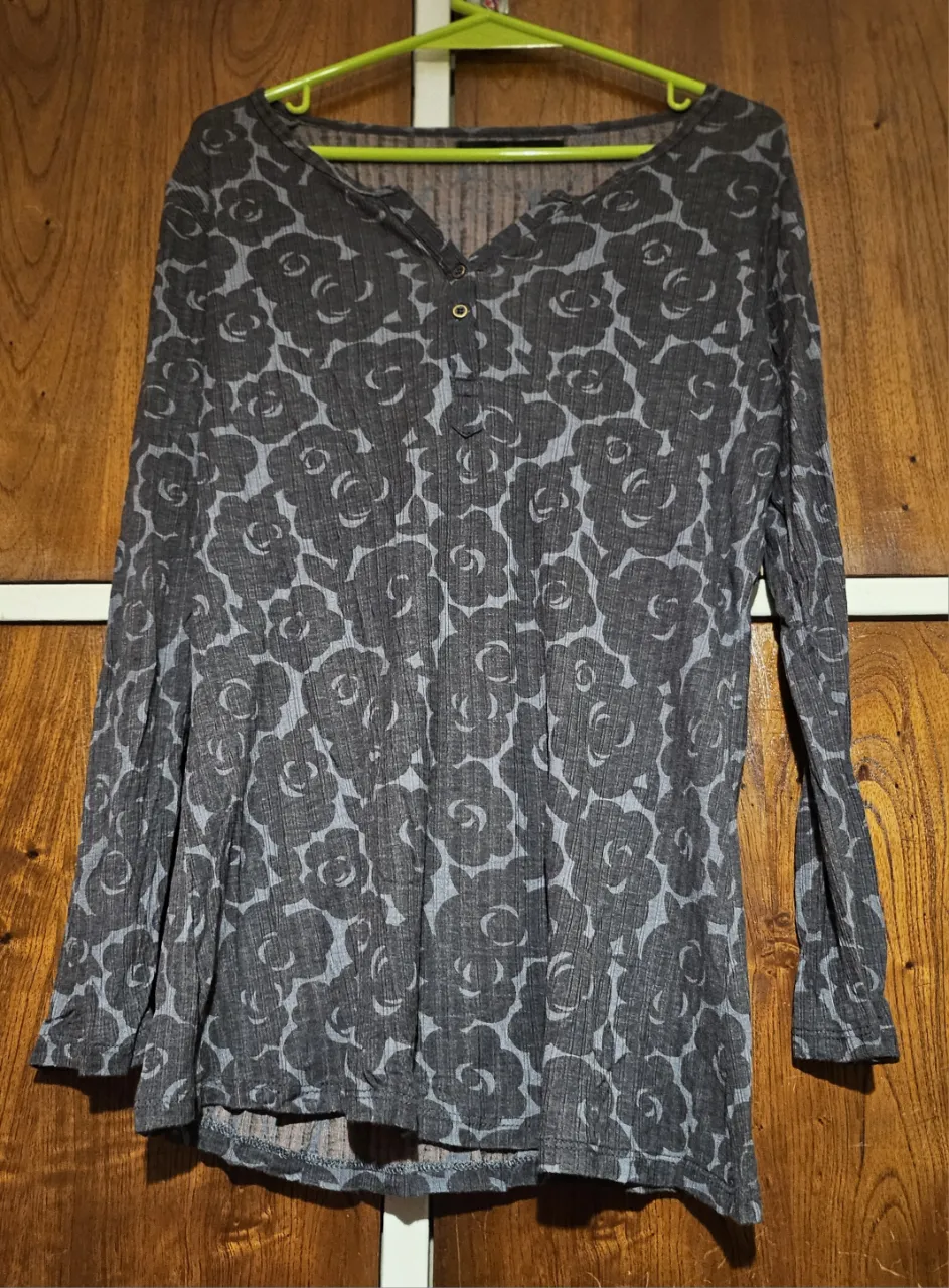 Blusa de manga larga para mujer, con estampado floral en tonos grises. Cuello en V y botones decorativos. Ideal para un look casual y cómodo.