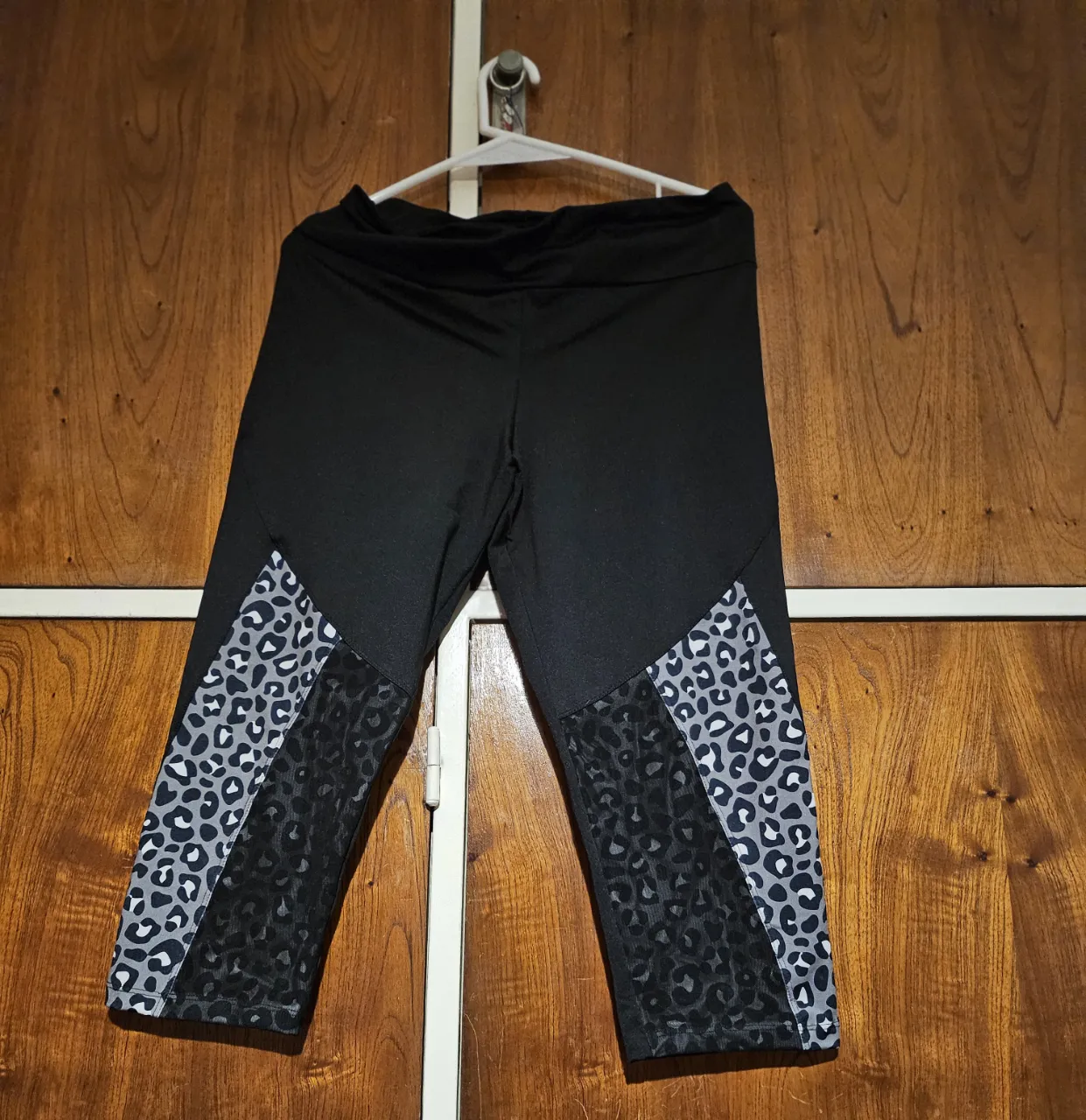 Calza deportiva capri para mujer, de color negro con detalles en gris y estampado de animal print en los laterales. Ideal para actividades físicas.