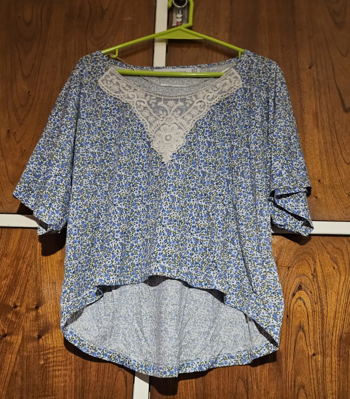 Blusa de mujer con estampado floral en tonos azules y blancos. Cuello redondo con detalle de encaje y mangas cortas con volados. Ideal para un look casual y fresco.