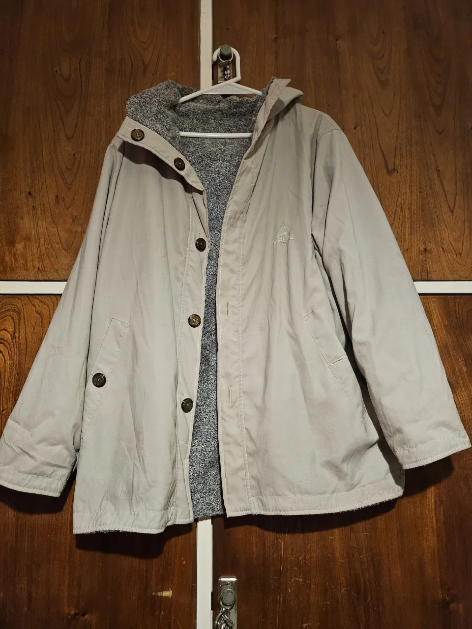 Campera reversible para mujer, con capucha y botones. Un lado es de color crudo y el otro gris, ideal para el invierno. Perfecta para un look casual y abrigado.