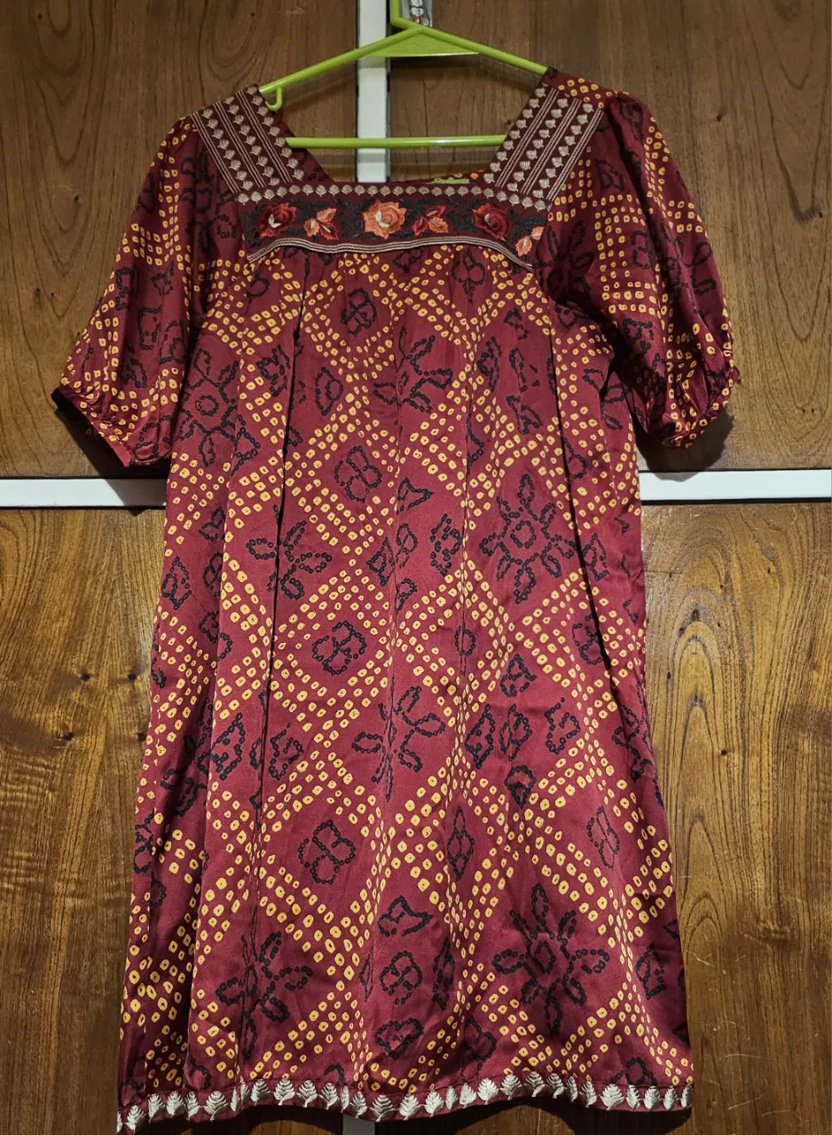 Vestido midi de mujer con estampado geométrico en tonos rojo y amarillo. Diseño con mangas cortas abullonadas y cuello cuadrado con detalles bordados. Ideal para un look casual y cómodo.