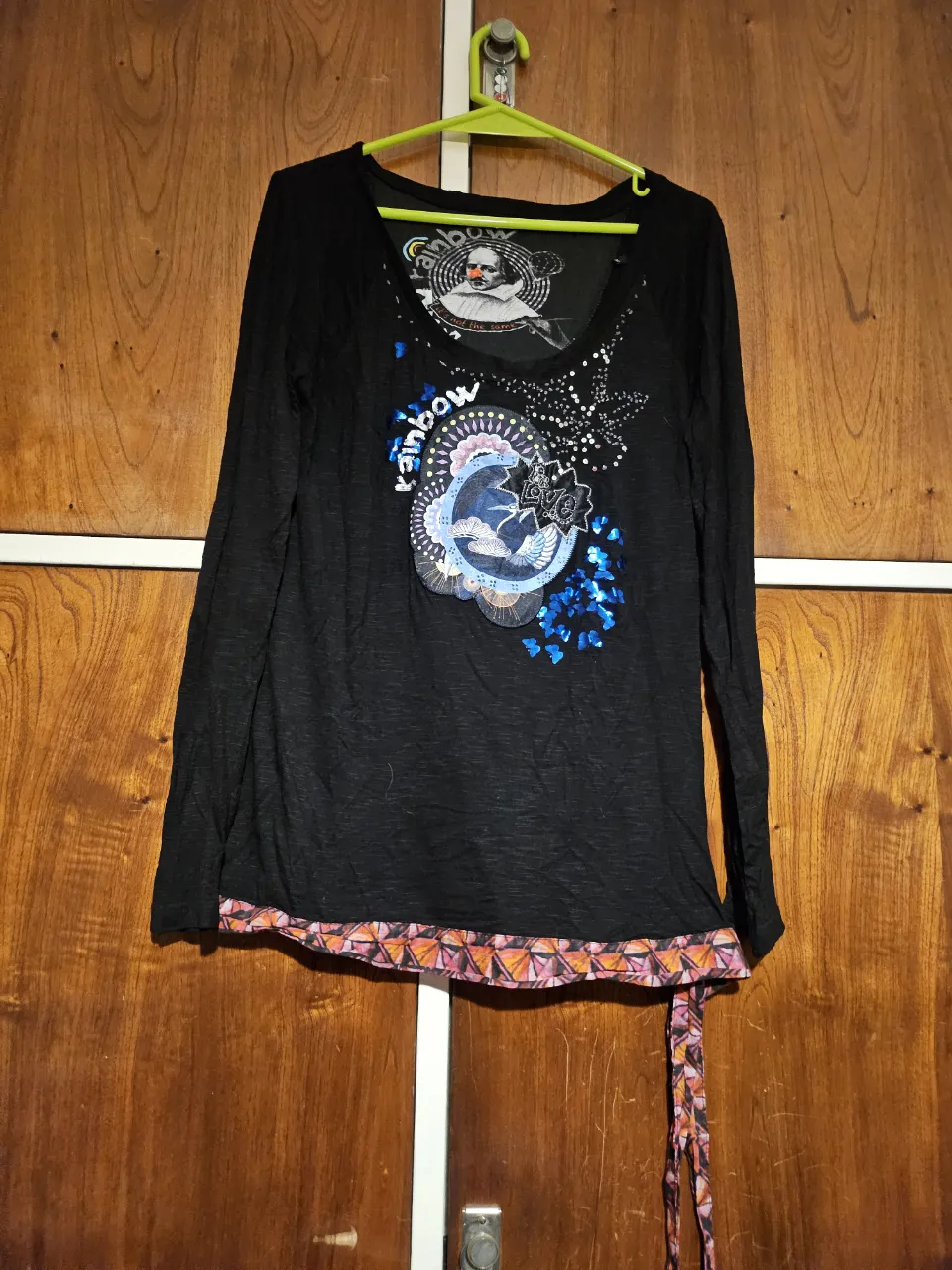 Remera manga larga negra con estampado frontal de diseño artístico y detalles en la parte inferior. Ideal para un look casual y con estilo.