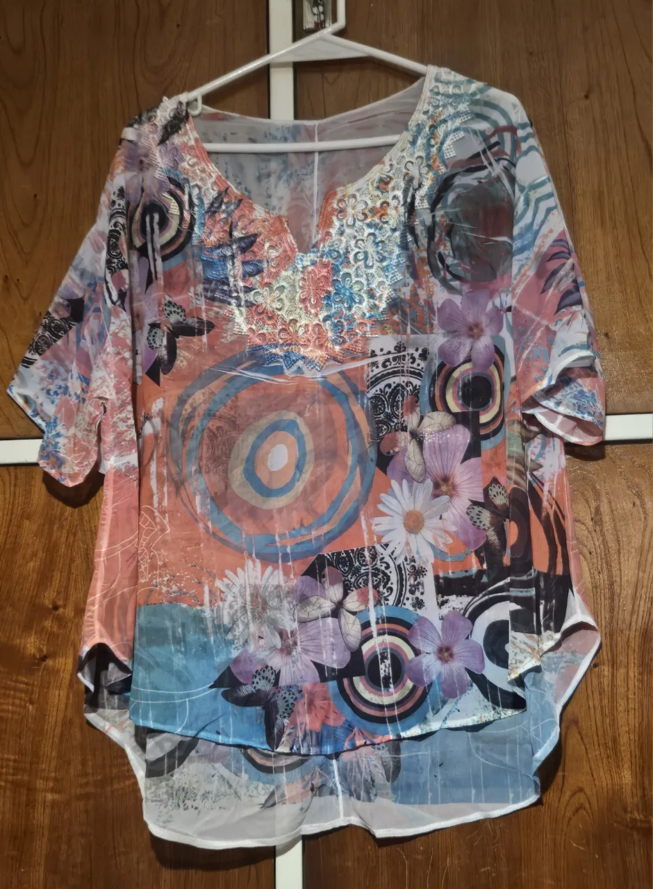 Blusa de mujer con estampado floral y detalles abstractos. Diseño holgado con mangas cortas y escote en V. Ideal para un look casual y fresco.