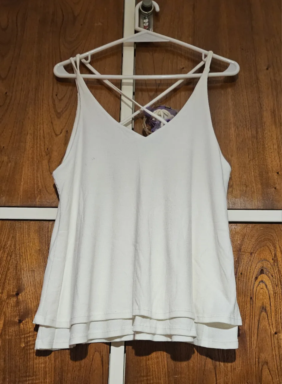 Top blanco con diseño de espalda cruzada y volados en la parte inferior. Ideal para un look fresco y moderno.