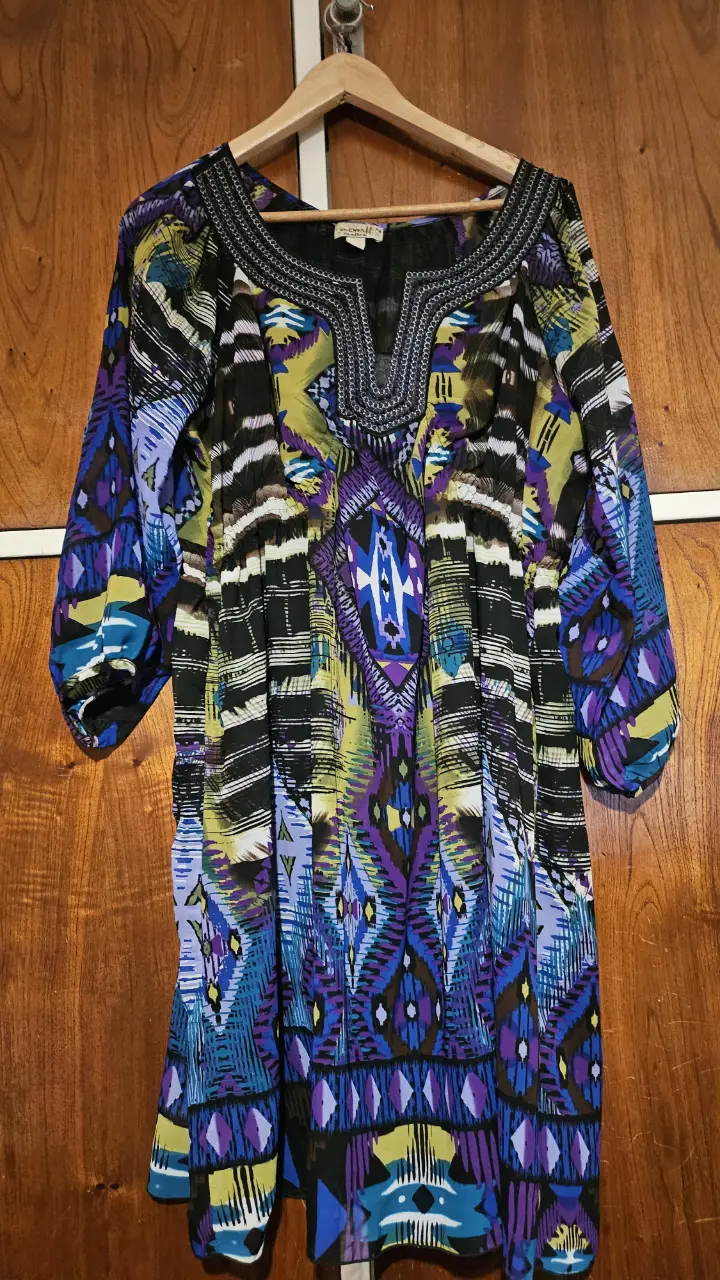 Vestido midi con estampado geométrico en tonos azules, morados, amarillos y negros. Mangas 3/4 y escote en V. Ideal para un look bohemio y casual.