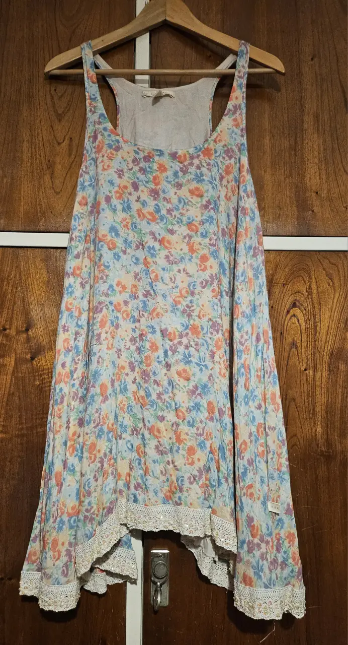 Musculosa de mujer con estampado floral en tonos pastel. Diseño suelto y ligero, ideal para el verano. Detalles de encaje en el borde inferior.