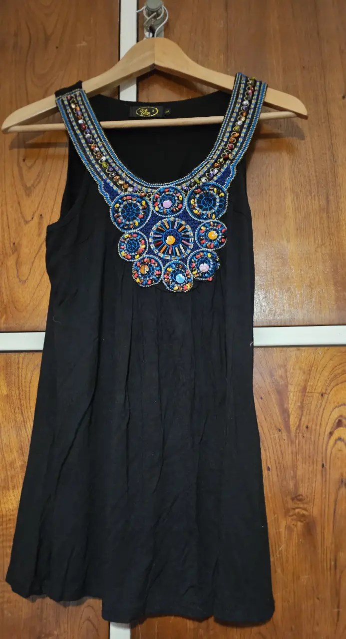 Vestido negro corto con detalles bordados en el cuello. Ideal para una salida o fiesta.