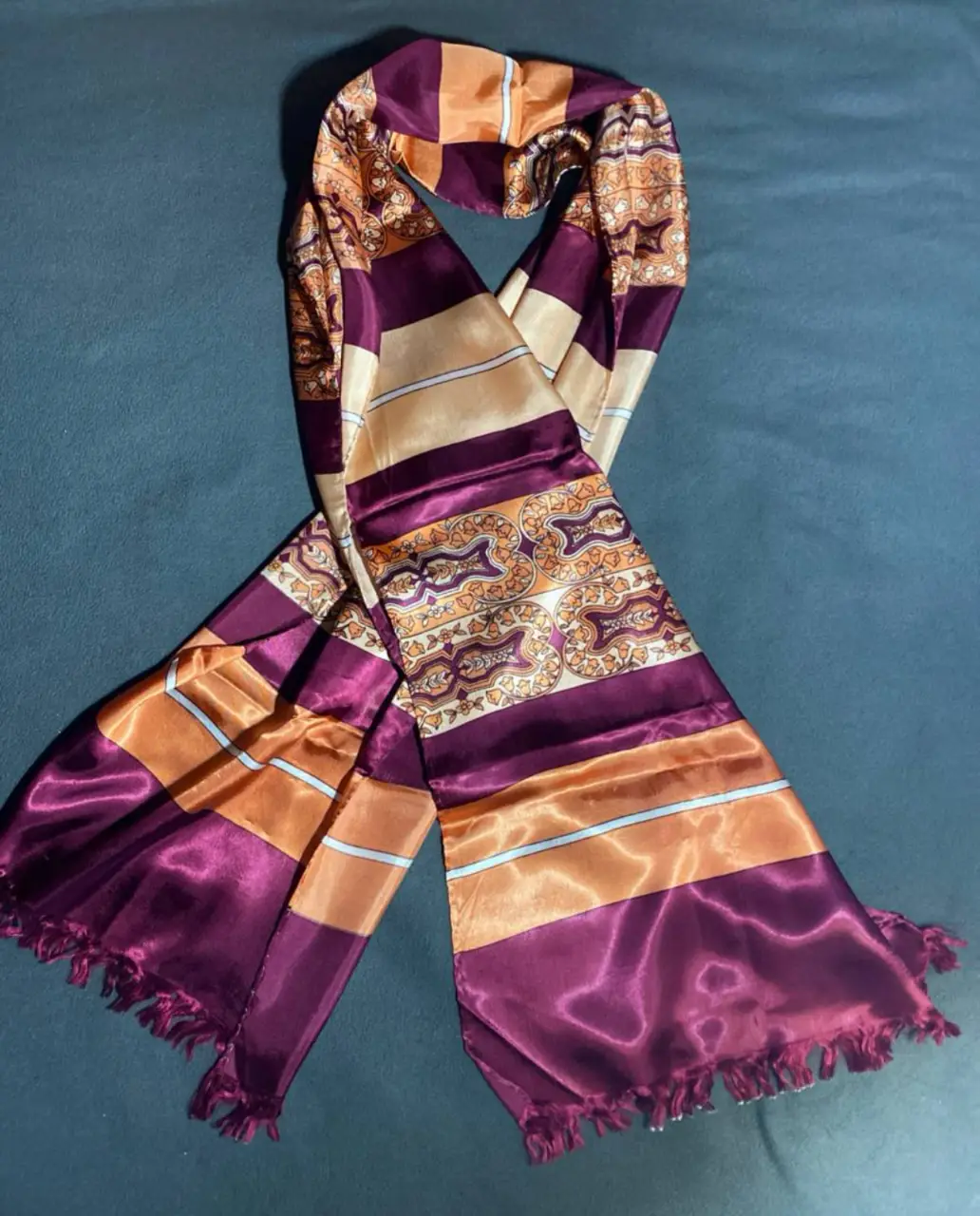 Pañuelo de seda con diseño paisley en tonos borgoña, naranja y dorado. mide 1.60 de largo y 37cm de ancho